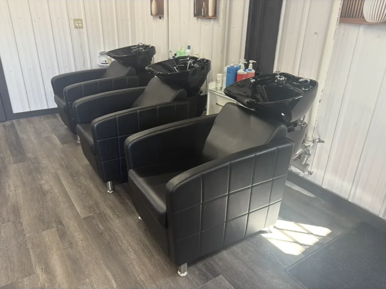 salon, chairs, shampoo, basins, wooden floor, white walls, sunlight, shelving, bottles